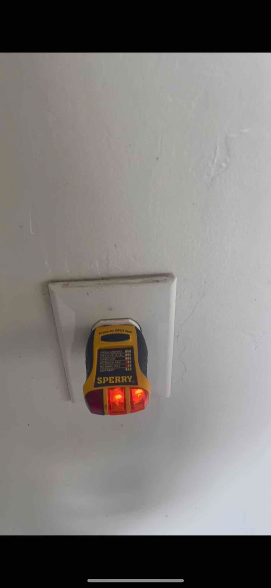 Receptacle tester positioned at an outlet during documented electrical checks
